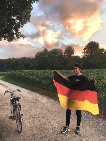Estudiante con la bandera alemana durante intercambios en Alemania, combinando naturaleza, movilidad diaria y sistema educativo.