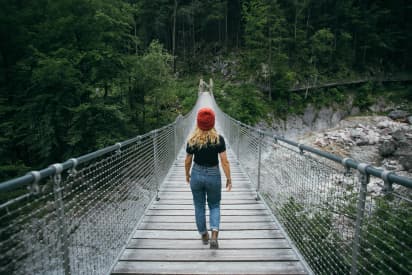 Estudiante cruzando un puente en la naturaleza, símbolo de crecimiento personal durante un año escolar en Canadá.