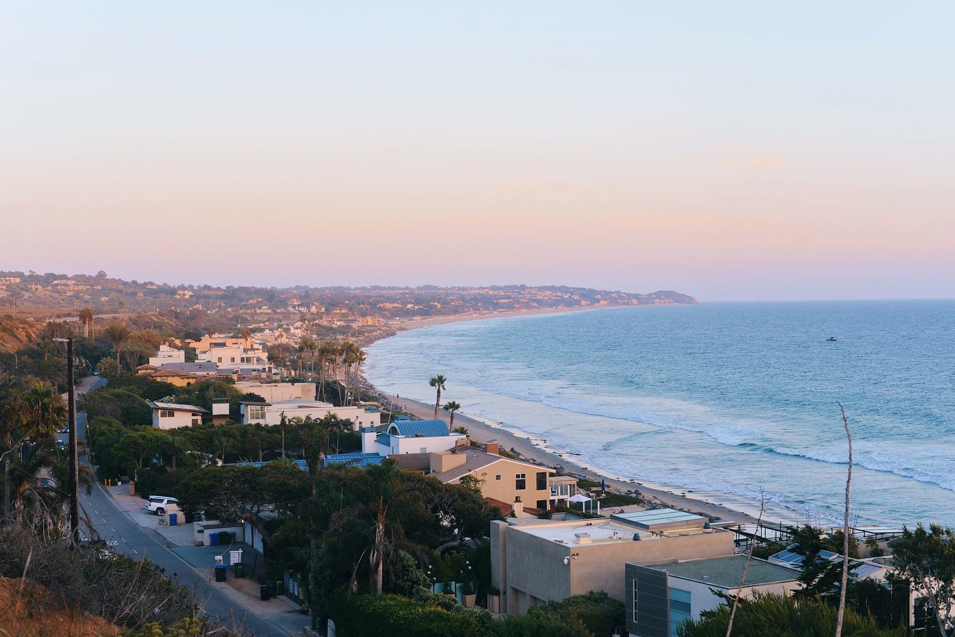 Vista panorámica de la costa de California al atardecer, con viviendas y océano, paisaje típico durante un año escolar en USA.