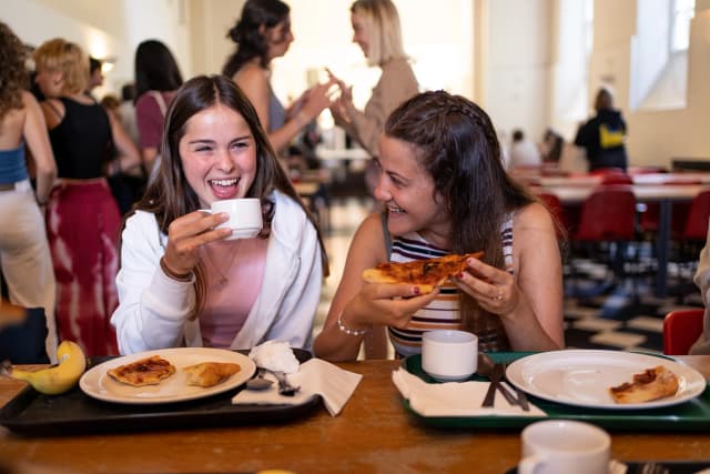 Studenti in vacanza studio a Inghilterra che condividono un pasto, vivendo esperienze culturali e migliorando l'inglese in un ambiente internazionale