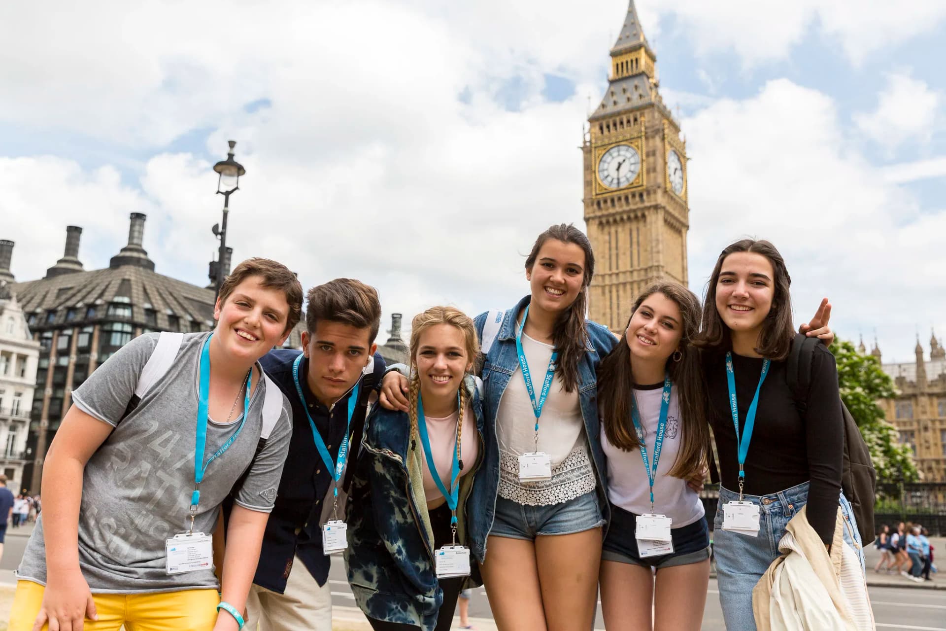 Gruppo di studenti in vacanza studio a Londra, sorridenti davanti al Big Ben, mentre esplorano la città e imparano l'inglese.